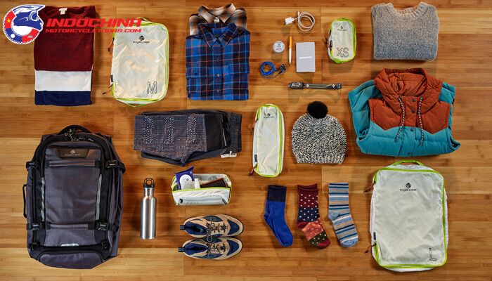 Flat lay of essential items for a motorbike tour, including clothing, gear, and accessories